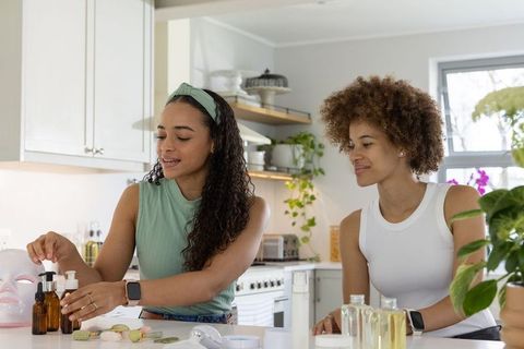 African american women preparing diy natural skincare with amber droppers and facial mask
