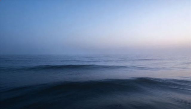 Calm ocean waves stretching into misty horizon at dawn creating serene minimalist seascape