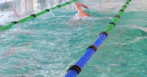 Male Swimmer Swimming Front Crawl in Indoor Pool with Blue and Green Lane Ropes