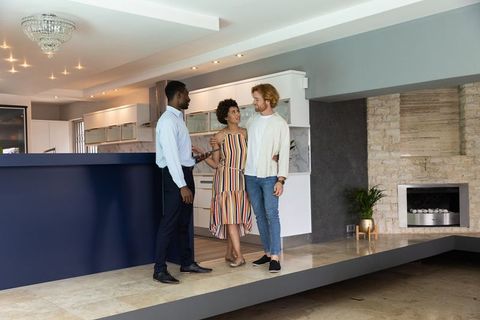 Real Estate Agent Discussing With Couple in Modern Luxury Kitchen