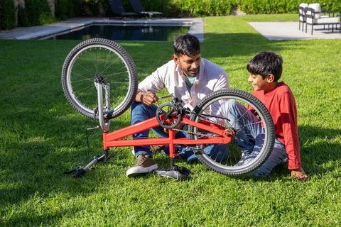 Father and son bonding over bicycle repair outdoors by pool