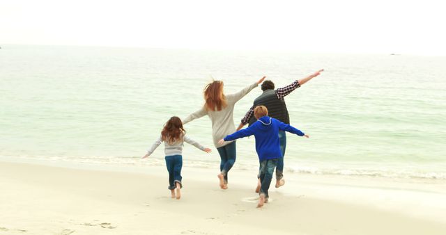 Family running together on beach with arms outstretched, enjoying tropical vacation at sunset. Use for travel promotions, family activity advertisements, lifestyle blogs, or wellness campaigns.