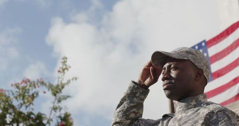 Proud soldier saluting near american flag outdoors