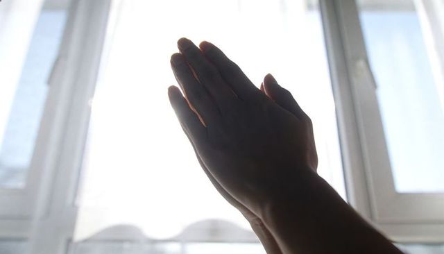 Hands pressing together silhouette at bright window morning light spiritual moment