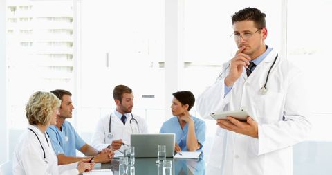 Confident Doctor Using Tablet During Medical Team Meeting - Download Free Stock Images Pikwizard.com
