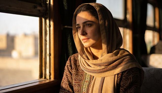 Gazing woman wearing patterned scarf on vintage train catching golden hour light
