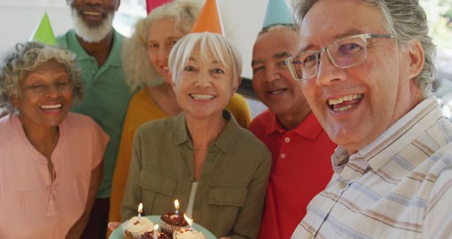 Portrait of happy senior diverse people at birthday party with cake at retirement home. healthy, active retirement and body inclusivity.