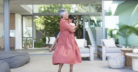 Loving grandmother embracing little girl on patio of modern home