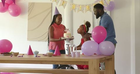 Family Birthday Celebration with Mother Bringing Cake to Smiling Child