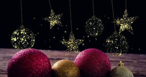 Golden stars and glittering baubles on wooden surface