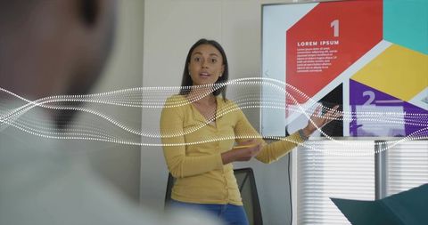Female presenter pointing at numbered infographic slide with digital wave overlay in office