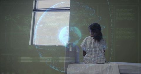 Child in medical gown sitting on exam table facing window with digital globe projection