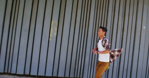Young Man Running Energetically Past Urban Wall