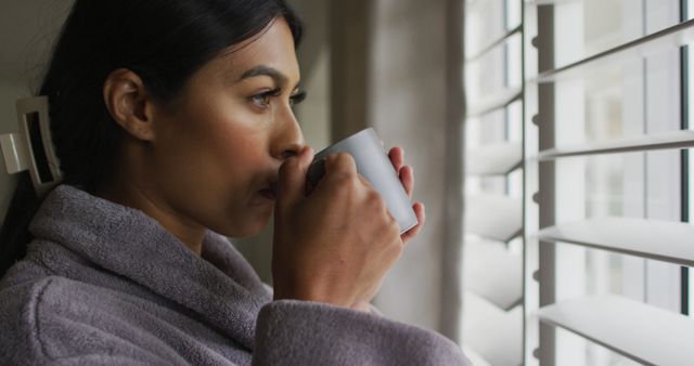 Image of biracial woman in rope with coffee looking outside window - Download Free Stock Photos Pikwizard.com