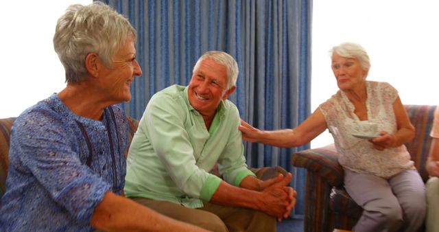 Group of happy senior friends interacting while having tea at home 