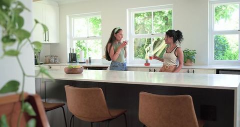 Friends chatting over iced drinks at modern minimalist kitchen island