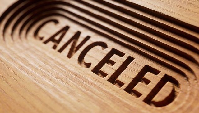 Recessed canceled lettering carved into wooden panel with layered grooves and shadow