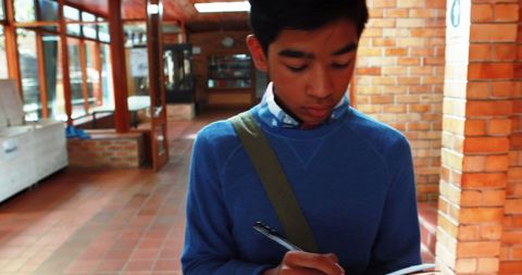 Focused asian teen student writing in notebook