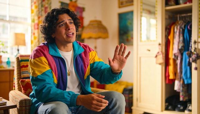 Hispanic man gesturing while chatting in colorful retro room wearing colorblock windbreaker