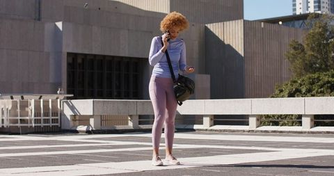 Urban fitness moment: woman checking smartwatch while talking on phone