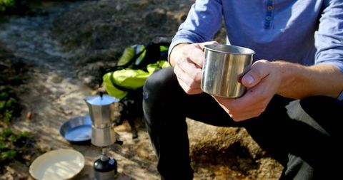 Hiker Enjoying Hot Drink in Mountain Setting While Climbing