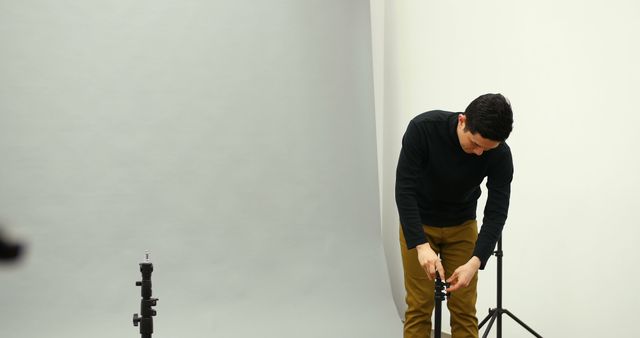 Photographer Adjusting Tripod in Studio - Download Free Stock Images Pikwizard.com