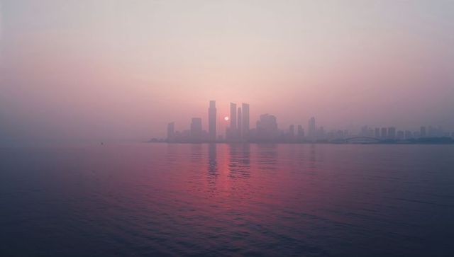 Serene Waterfront Skyline at Sunrise with Skyscraper Reflections