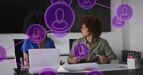 Collaborating over blueprint and laptop with purple network overlay connecting team