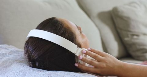 Woman Relaxing on Couch Listening with White Headphones
