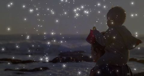 Mother carrying child on shoulders at twilight beach with sparkling star overlay