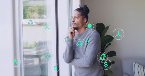 Man contemplating renewable energy investments with AR sustainability icons on glass door