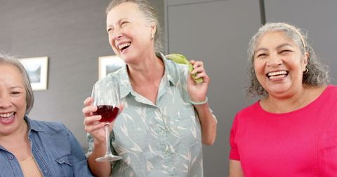 Senior Friends Laughing and Enjoying Food Together Indoors