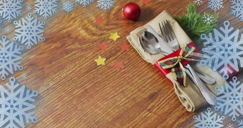 Rustic holiday tabletop cutlery wrapped in tartan ribbon with snowflake border