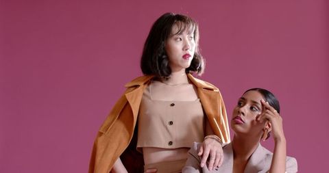 Confident women posing in sophisticated fashion against pink background