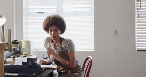 Female Jeweller Creating Sketches in Workshop with Natural Light