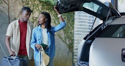 Couple Preparing for Road Trip with Luggage and Travel Documents
