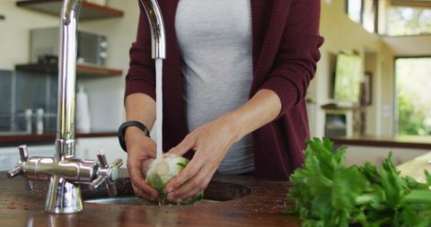 Pregnant woman washing vegetables for healthy cooking