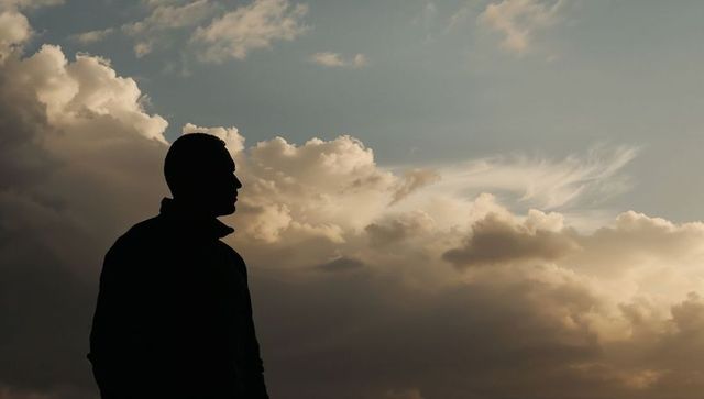 Silhouette of Man Against Dramatic Cloudscape at Dusk