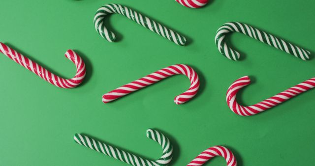 Red and green striped candy canes on green background. christmas, tradition and celebration concept image.