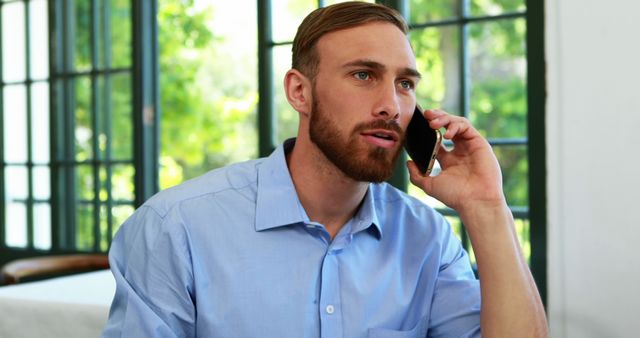 Businessman Talking on Smartphone in Office with Large Windows - Download Free Stock Images Pikwizard.com