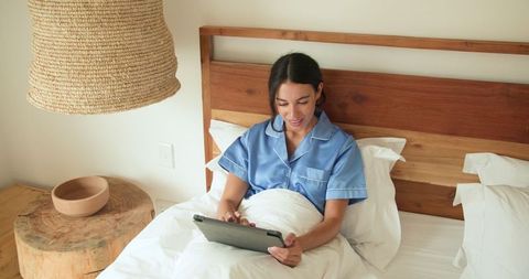 Woman in Blue Pajamas Using Tablet in Bed for Relaxation