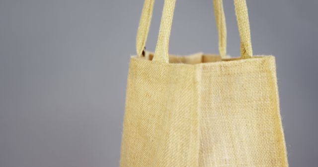 Close up of yellow canvas shopping bag on grey background. Shopping, clothes and colour concept, unaltered.