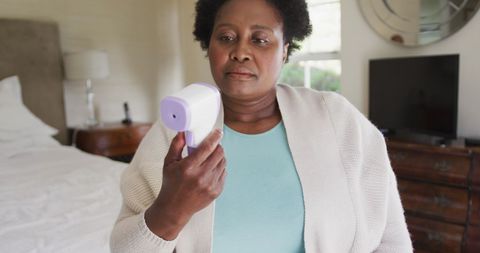 Senior woman measuring temperature at home during pandemic