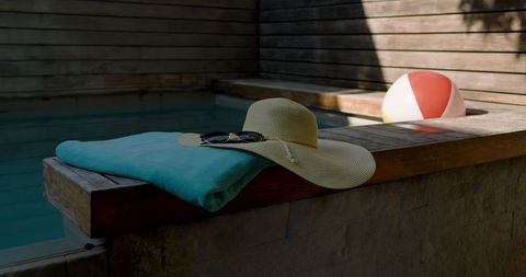 Serene poolside leisure with straw hat and beach ball