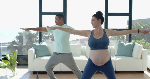 Pregnant Woman and Her Partner Practicing Yoga at Home Together