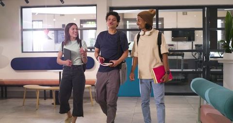 Diverse Students Walking and Talking on Modern Campus Hallway with Backpacks and Notebooks