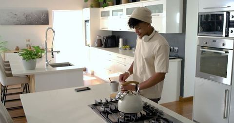 Young man preparing morning coffee in bright minimalist contemporary kitchen