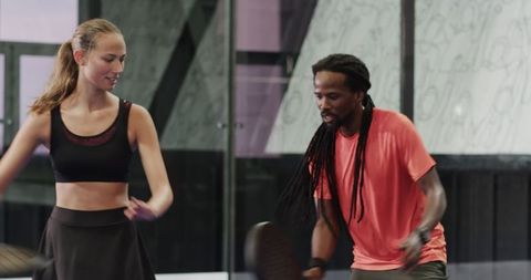 Energetic duo playing padel tennis on indoor court