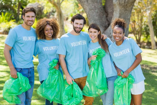 Portrait of volunteer group posing while collecting rubbish in park