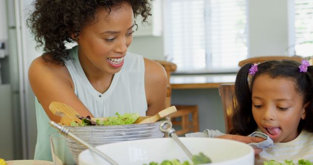 Mother preparing salad with daughter in modern kitchen - Download Free Stock Images Pikwizard.com